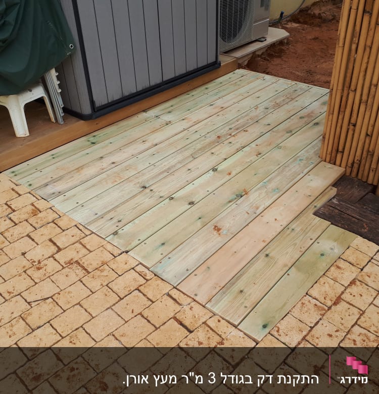 רצפת עץ חדשה ליד קיר במבוק בגינה